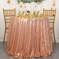 the table is covered with gold sequins and decorated with greenery on top