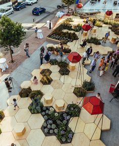 an aerial view of people walking and sitting on benches in the middle of a city