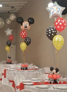 mickey mouse balloons are on the tables at a party