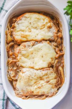 two pieces of bread covered in sauce and cheese on top of a white casserole dish