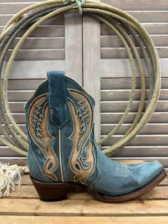 Looking for a stylish and comfortable boot? Look no further than the Corral Circle G Women's Distressed Blue & Tan Inlay Ankle Boot. Made from genuine leather, this boot stands out with its intricate details. With its quality and craftsmanship, Circle G Boots are sure to become a favorite brand for those who love cowgirl boots. Handcrafted by more than 90 artisans. Authentic Cowgirl Style Snip Toe Pull Tabs 7" Shaft Height 1.5" Cowboy Heel Cowhide Outsole Pig Lining Goodyear Welt Color: Distress Blue Leather Heeled Boots With Snip Toe, Rustic Ankle Boots With Reinforced Heel, Western Style Ankle-high Leather Boots, Blue Snip Toe Boots For Rodeo, Western Blue Boots With Round Toe, Blue Western Boots With Round Toe, Blue Snip Toe Boots With Reinforced Heel, Western Blue Leather Heeled Boots, Blue Leather Western Heeled Boots