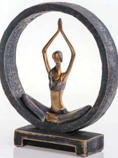 a statue of a woman sitting in a yoga pose with her hands up to the side