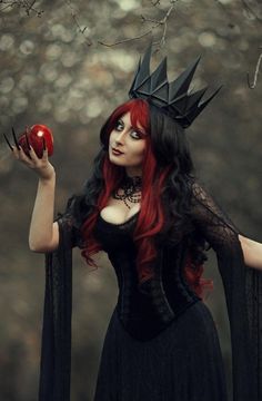 a woman with red hair wearing a black dress and crown holding an apple in her hand