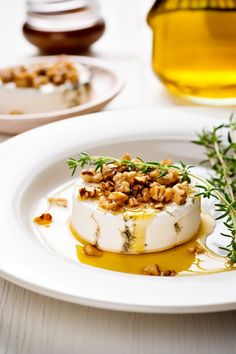 a white plate topped with food next to a bottle of olive oil and a sprig of rosemary