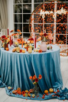 the table is set with orange flowers and candles for an elegant wedding reception in front of a large window