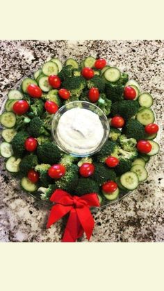 a wreath made out of cucumbers and tomatoes with a dip in the middle