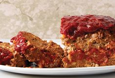 a piece of meatloaf on a plate with another slice cut in half next to it