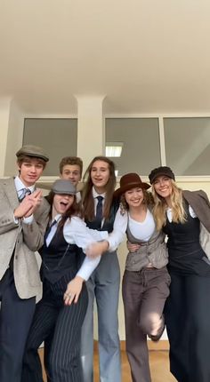 a group of young people standing next to each other in front of a wall with windows