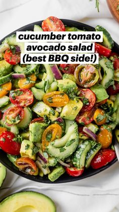 a salad with cucumbers, tomatoes and avocado in a black bowl