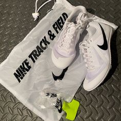 a pair of white nike sneakers sitting on top of a plastic bag next to a yellow shoe