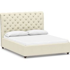 an upholstered bed with white linens and nail polishing on the headboard