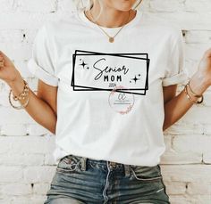 a woman wearing a white t - shirt with the words senior mom printed on it