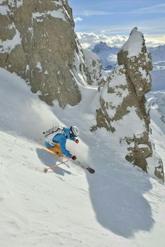 a man riding skis down the side of a snow covered slope on top of a mountain