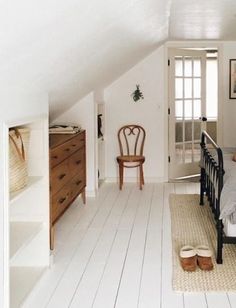 an attic bedroom with white floors and wooden furniture, including a black iron bed frame