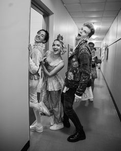 three people in costumes standing next to each other on a hallway with an open door