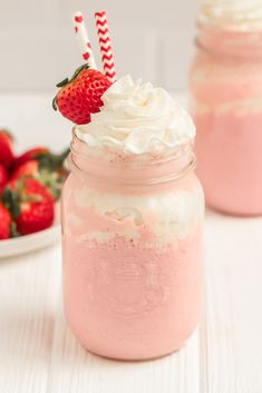 strawberry milkshake in a mason jar with strawberries on the table behind it