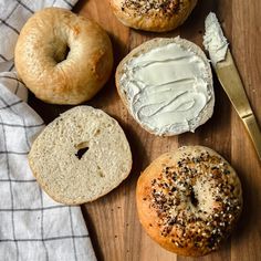 four bagels with cream cheese and sprinkles on a wooden cutting board