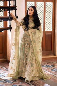 a woman in a green and gold outfit with long black hair standing on a tiled floor