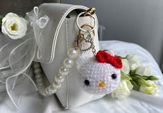 a white purse with a hello kitty keychain attached to it