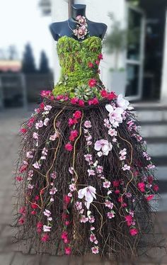 a dress made out of plants and flowers on a mannequin's head