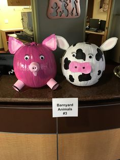 two pig sculptures sitting on top of a counter next to each other in front of a sign that says barnyard animals