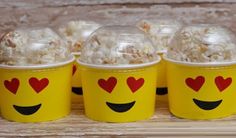 three yellow cups filled with popcorn and hearts on top of each cup are sitting on a wooden table