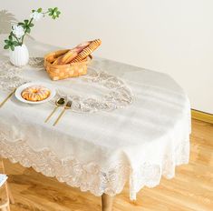 a table topped with bread and pastries next to a vase filled with flowers on top of a hard wood floor