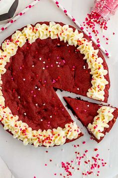 a red velvet cake with white frosting and sprinkles on the side