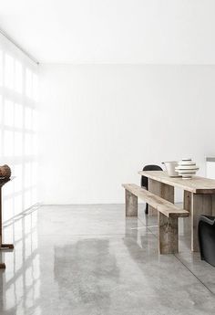 a table and bench in a room with white walls