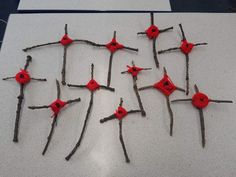 several branches with red buttons on them sitting on a white table next to each other