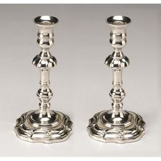 two silver candlesticks sitting next to each other