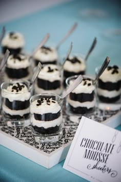 small desserts are sitting on a tray with spoons in each one and an empty card next to them