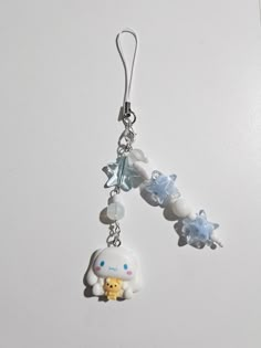 a pair of earrings with charms attached to them on a white surface, featuring an animal and snowflakes