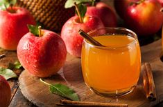 an apple cider with cinnamon sticks in it next to apples on a cutting board