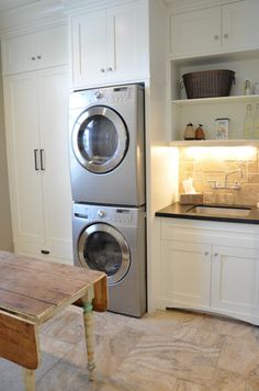 a washer and dryer sitting in a kitchen next to a counter with a wooden table