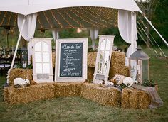 hay bales are stacked on top of each other in front of a chalkboard sign