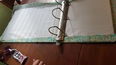 someone is cutting out the paper on top of an empty binder and wrapping it with twine