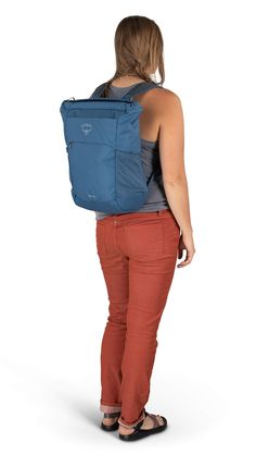 a woman is standing with her back to the camera and she has a blue backpack on