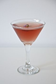 a glass filled with pink liquid sitting on top of a table