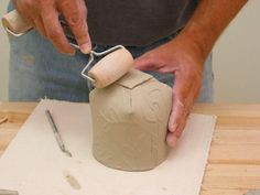 a man is making a vase out of clay with a rolling pin on the table