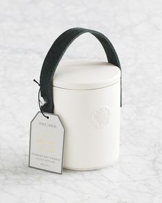 a white canister with a black ribbon around it and a tag on the side