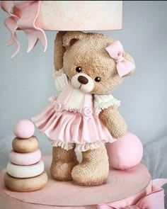 a brown teddy bear sitting on top of a pink cake