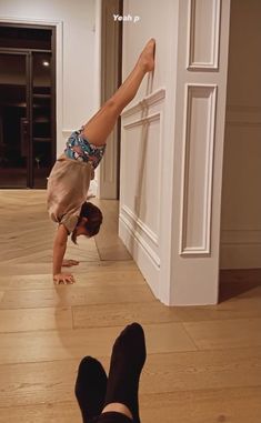 a person standing on one hand and doing a handstand in front of a wall