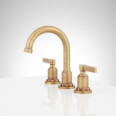 two brass faucets on a white surface