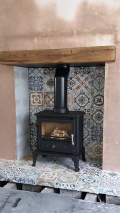 a wood burning stove in a room with tile flooring and wallpaper on the walls