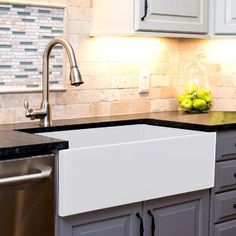 a kitchen with white cabinets and black counter tops, stainless steel dishwasher and sink