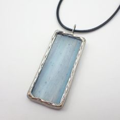 "Transparent, light blue textured stained glass pendant edged in silver, accented with twisted a silver wire. Add a 17-19\" adjustable black waxed cotton necklace cord for free or purchase an 18\" sterling silver cable chain necklace under options.   Actual Size: 2 1/16\" x 13/16\" Each item by Faerie Glass Is 100% uniquely hand-crafted with quality materials that are lead-free. NOTE - All photographs are taken in effort to best represent the actual product. Color of actual jewelry may vary slightly from photographs." Stained Glass Pendant, Cotton Necklace, Necklace Cord, Cable Chain Necklace, Blue Texture, Frozen In Time, Black Necklace, Waxed Cotton, Glass Pendant