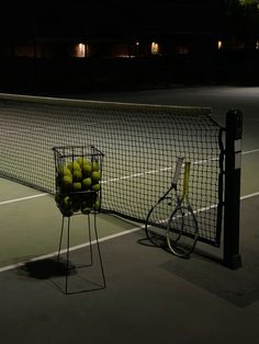 tennis balls in a basket next to a racket with a bicycle on the ground