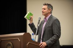 a man standing at a podium with a green box in his hand