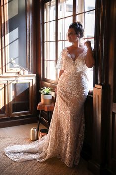 a woman in a wedding dress leaning against a window